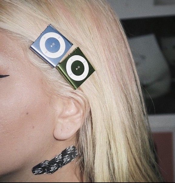 Blonde person wearing both blue and green iPod Shuffles clipped to their hair.