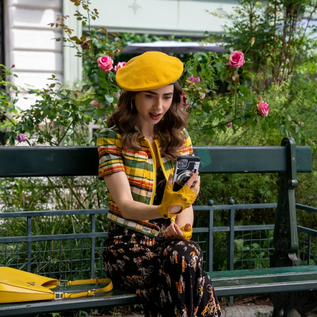 Emily in Paris wears a yellow beret and stares at her phone