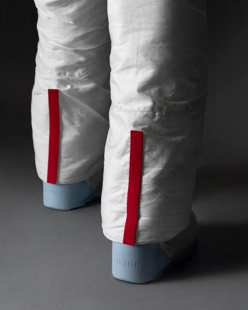 Back of the Prada Spacesuit's Legs: The lower part of the spacesuit shows white, heavily padded legs with small red stripes running vertically down the calves. The boot soles are light blue, adding contrast to the suit.