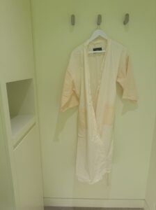 A neatly hung yellow robe on a wall hook in a minimalistic room, signifying the preparation stage of Neko Health’s scan process.