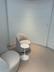 A quiet consultation space with two rounded chairs and a sleek white table, set against a clean, curved wall, designed for personalized doctor-patient discussions at Neko Health.