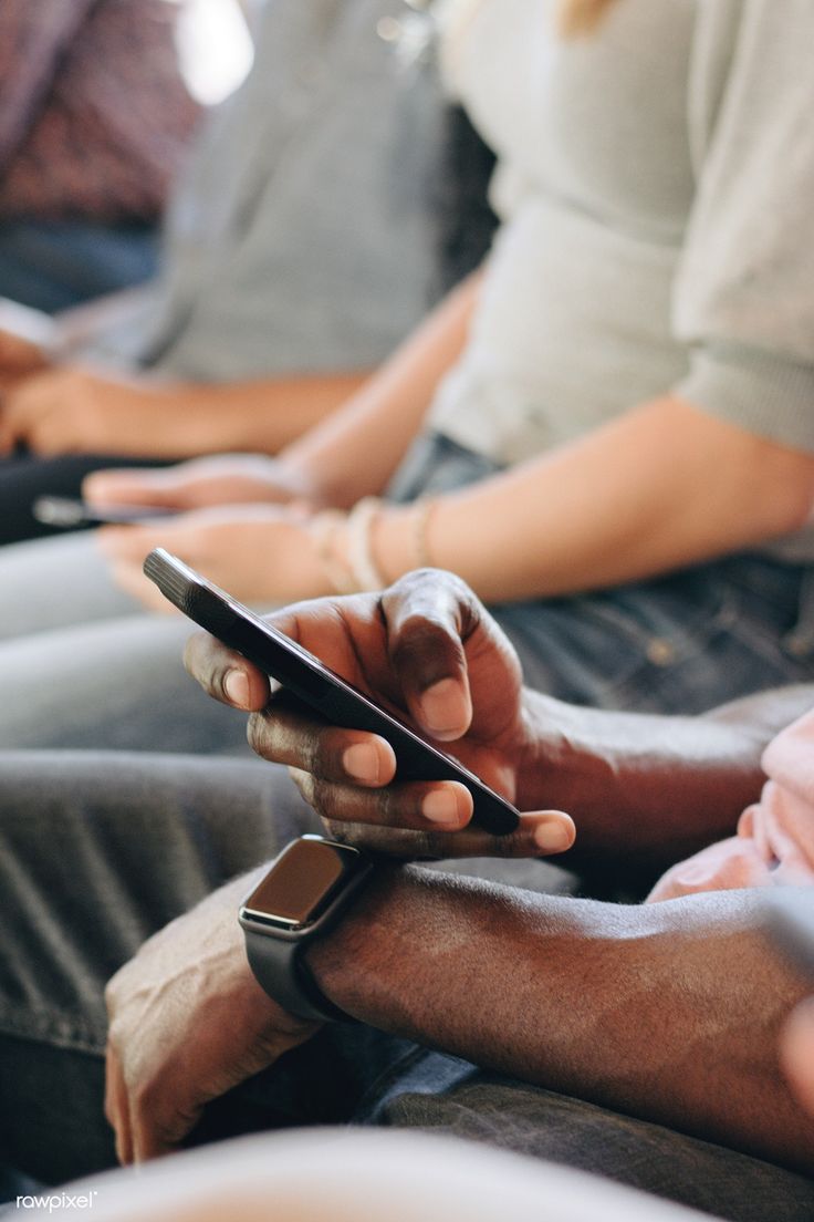 This may contain: two people sitting on a couch using their cell phones while one person holds the phone in his hand