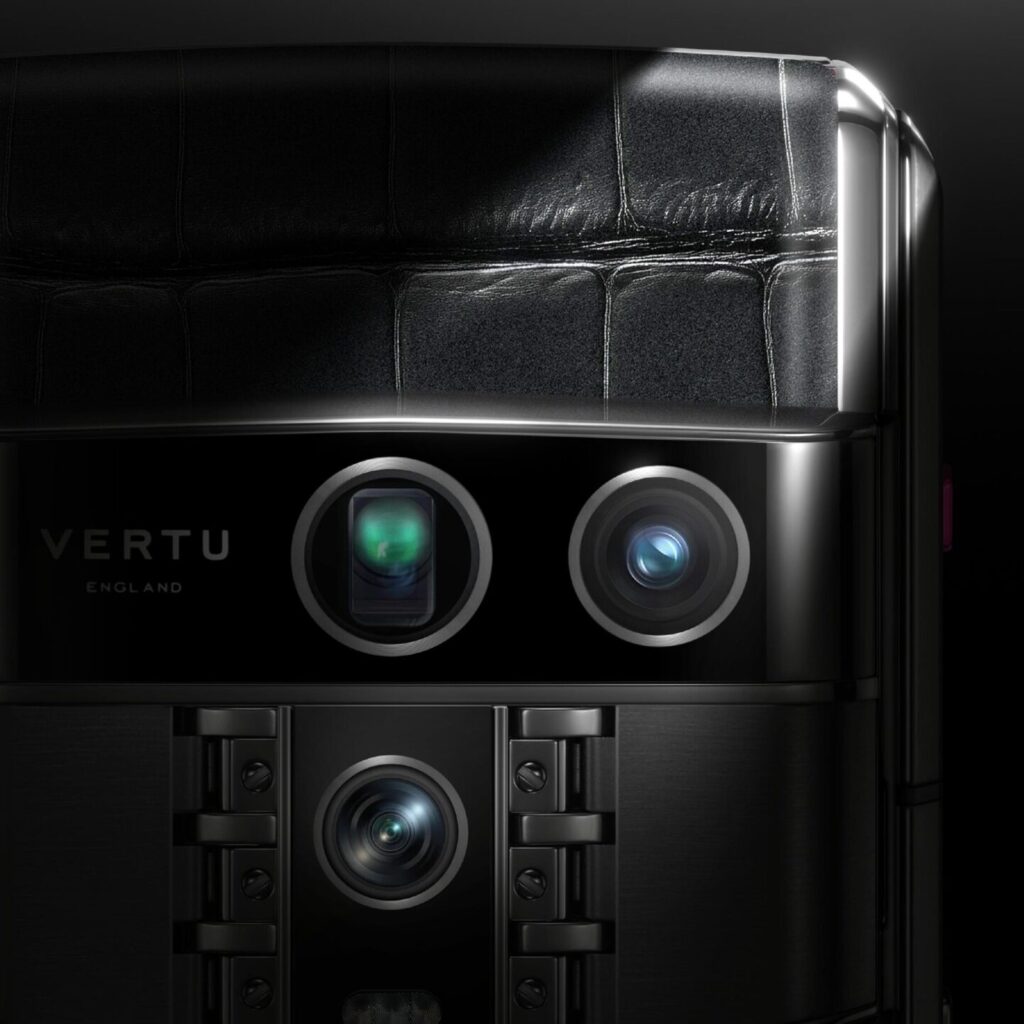 Close-up image of Vertu smartphone’s camera system showing three premium lenses with engraved leather texture and text detailing specifications: 50MP main, 50MP ultra wide, and 64MP telephoto.