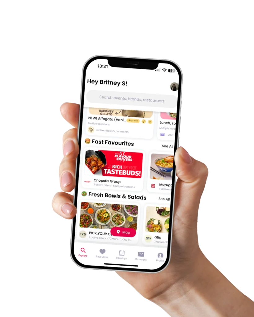 Hand holding a smartphone displaying the Invyted app interface with influencer offers, restaurant listings, and brand collaborations visible on screen.