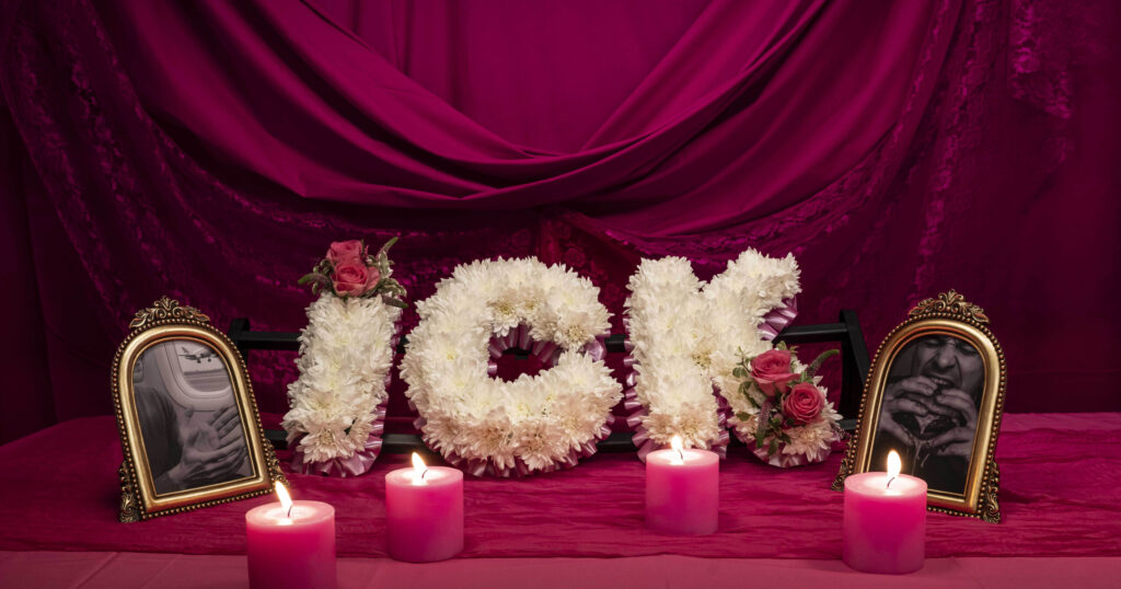 White floral arrangement spelling “ICK” with roses and pink candles against a fuchsia satin backdrop, representing Tinder’s symbolic farewell to superficial dating turn-offs.