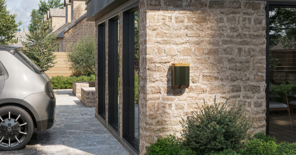 A sleek wall-mounted EV charger fixed to a Cotswold-stone house beside a modern car, demonstrating Simpson & Partners’ blend of design and function.