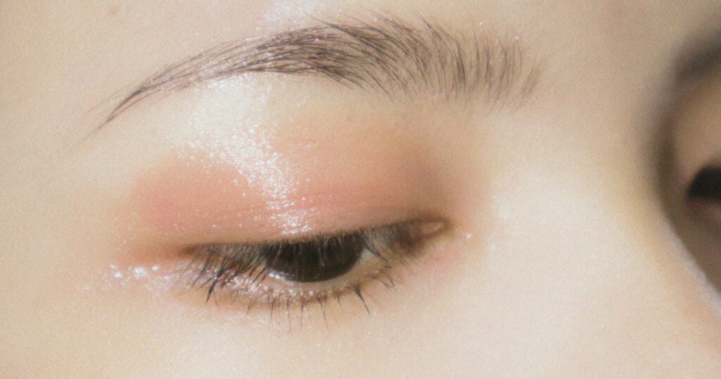 A close-up of a person’s eye and cheek showing luminous, dewy skin with soft peach-toned eyeshadow, illustrating the radiant effects associated with PRP and regenerative skincare treatments.