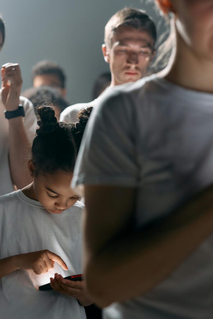 In a crowd of adults glued to their screens, one child mirrors their every move — proof that tech habits start younger than ever.