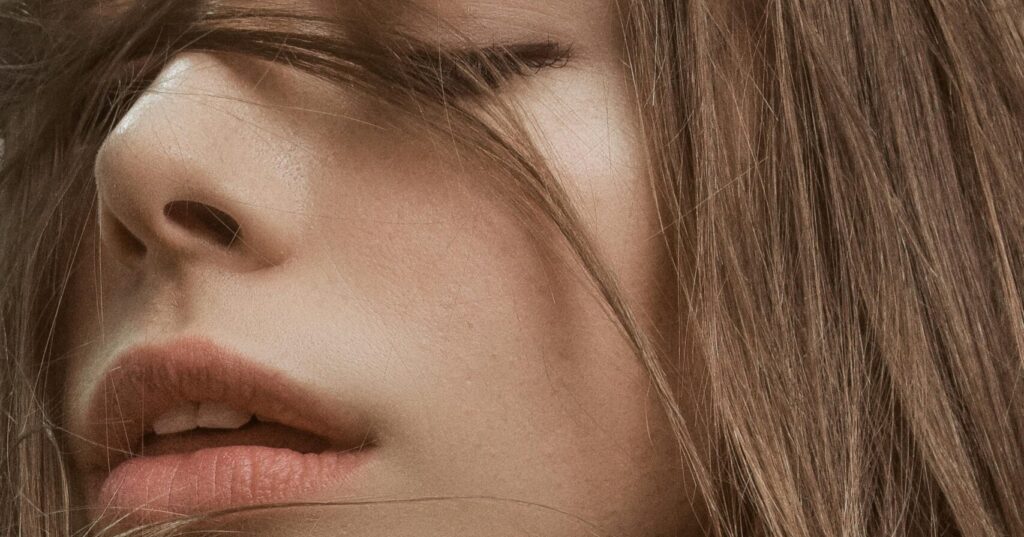 Close-up of a woman’s face and lips with natural light and tousled hair, illustrating smooth skin texture and natural glow for a collagen skincare article.