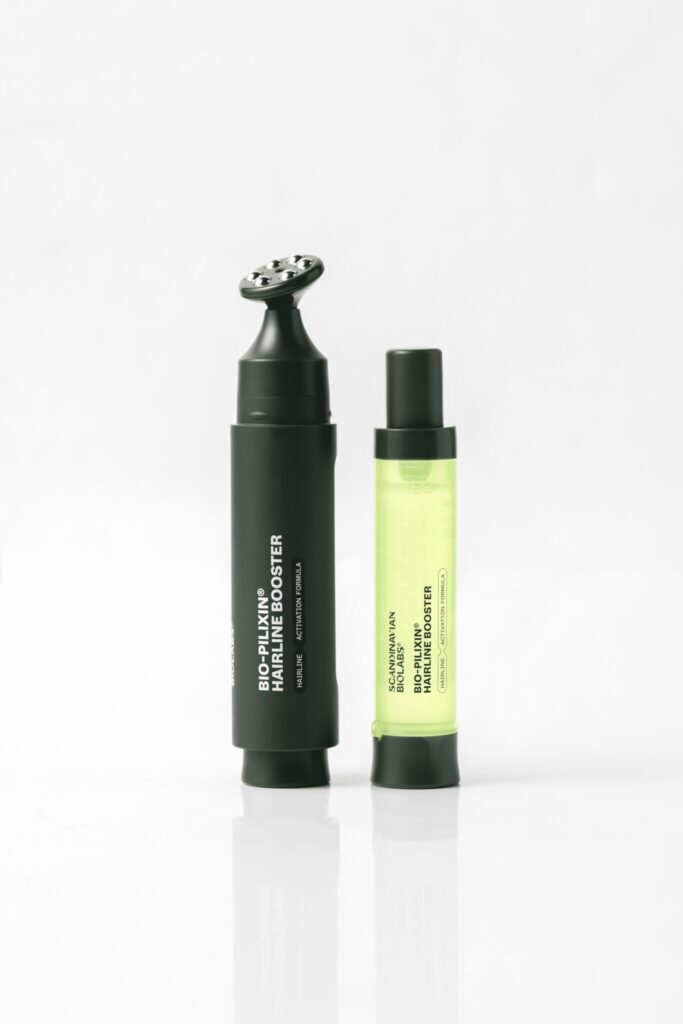 A photograph showing the Scandinavian Biolabs Bio-Pilixin Hairline Booster applicator and refill cartridge, highlighting its sleek refillable system and bright green serum.
