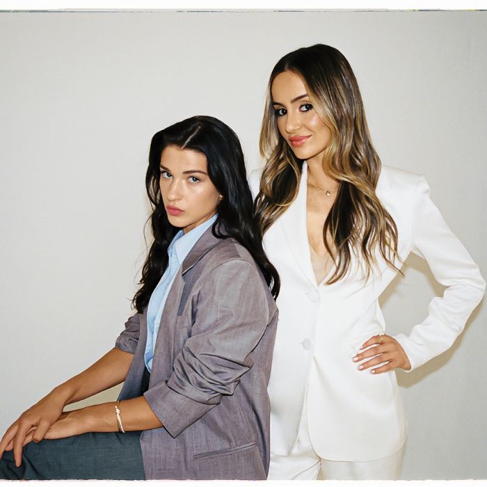 Phoebe Gates and Sophia Kianni, co-founders of fashion-tech startup Phia, pose together in tailored suits against a minimalist backdrop.