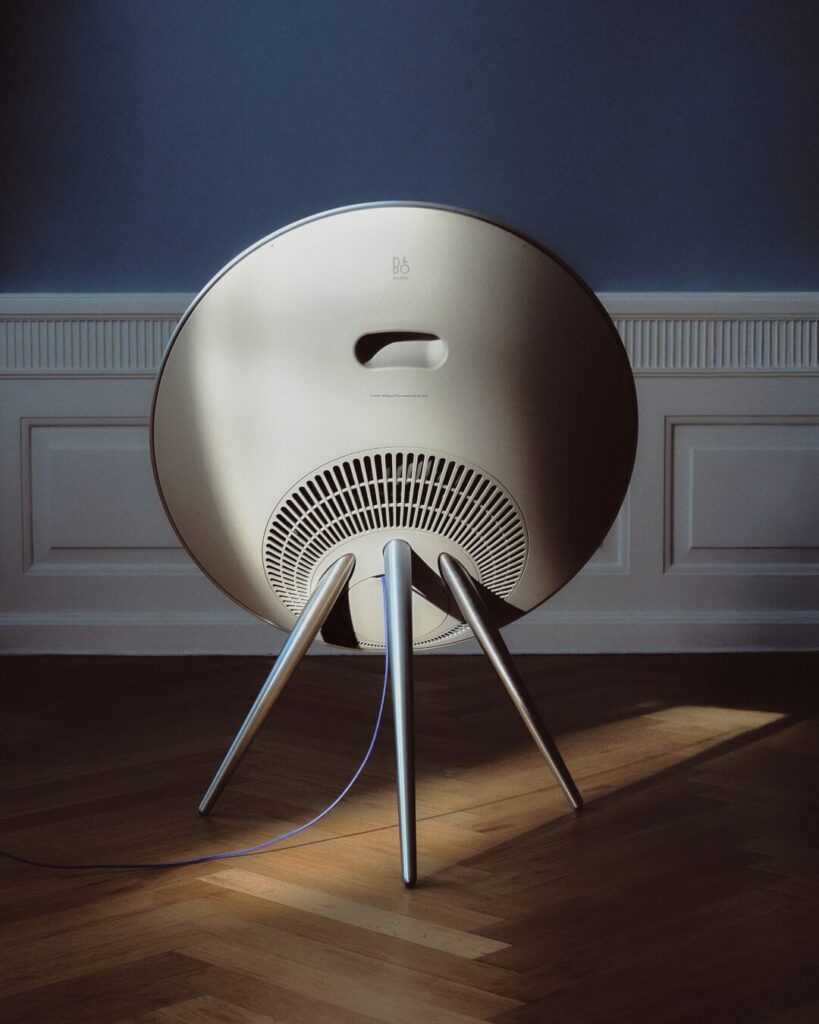 Rear view of Bang & Olufsen Beosound A9 Centennial Edition speaker showing brushed aluminium frame and blue power cable in a minimal Danish room.