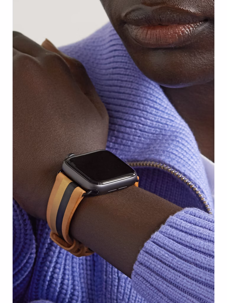 Close-up image of a model wearing an Apple Watch with a LA Californienne striped leather watch strap in tan, black and gold tones, styled with a lilac knit sweater.