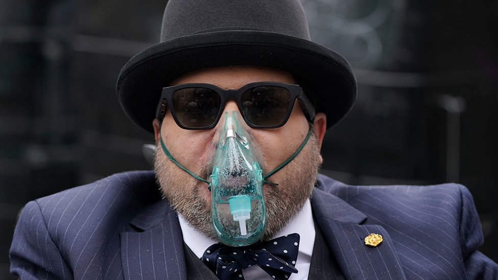 Promotional image from Prime Video documentary Nicholas Rossi: Conman and Predator showing Nicholas Rossi wearing sunglasses, a bowler hat and an oxygen mask, symbolising identity deception and modern true crime investigation.