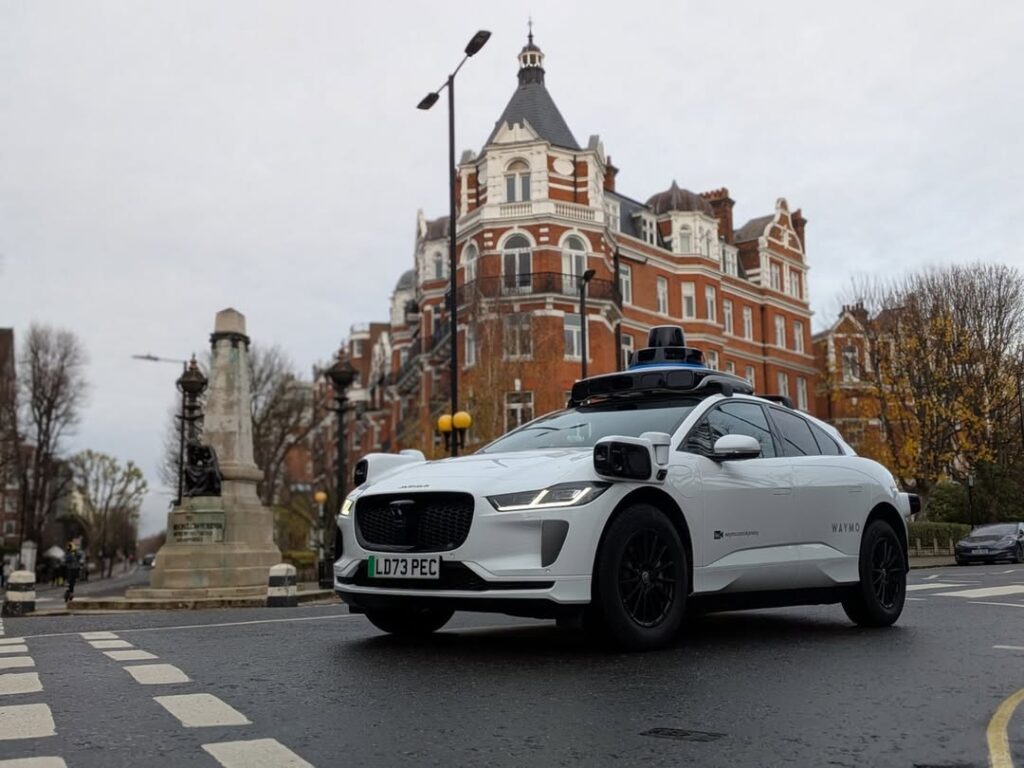 Waymo driverless car on a London street with historic buildings, showing autonomous vehicle technology being tested in the UK and raising questions about safety, accessibility and the future of taxi travel for women.
