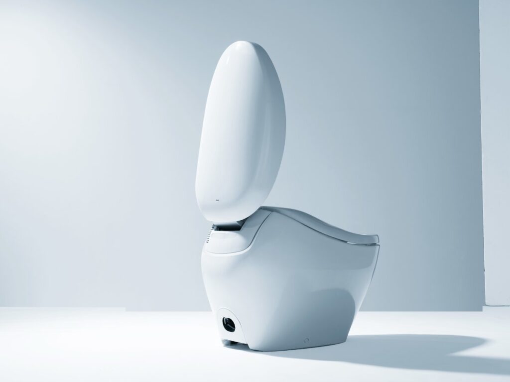A Japanese smart toilet with the lid open in a minimalist studio environment, showcasing the advanced design and built-in technology used to collect health and wellness data.