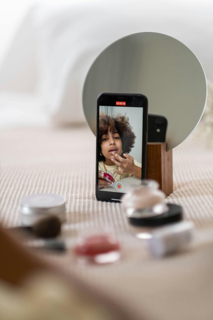 A beauty content creator filming a skincare routine on a smartphone placed in front of a mirror, representing influencer marketing in the beauty industry and creator-led product storytelling on social media.
