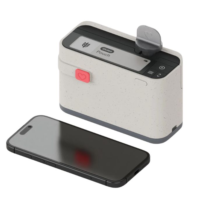 Portable Allergen Alert food scanner with smartphone placed beside it, designed to detect allergens and gluten in food samples using disposable testing pouches.
