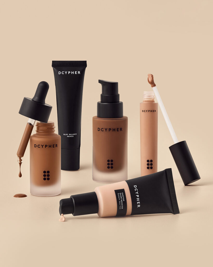 Studio image of DCYPHER Beauty’s full product collection, including AI-custom foundation, glow boosters and primers designed using personalised skin technology.