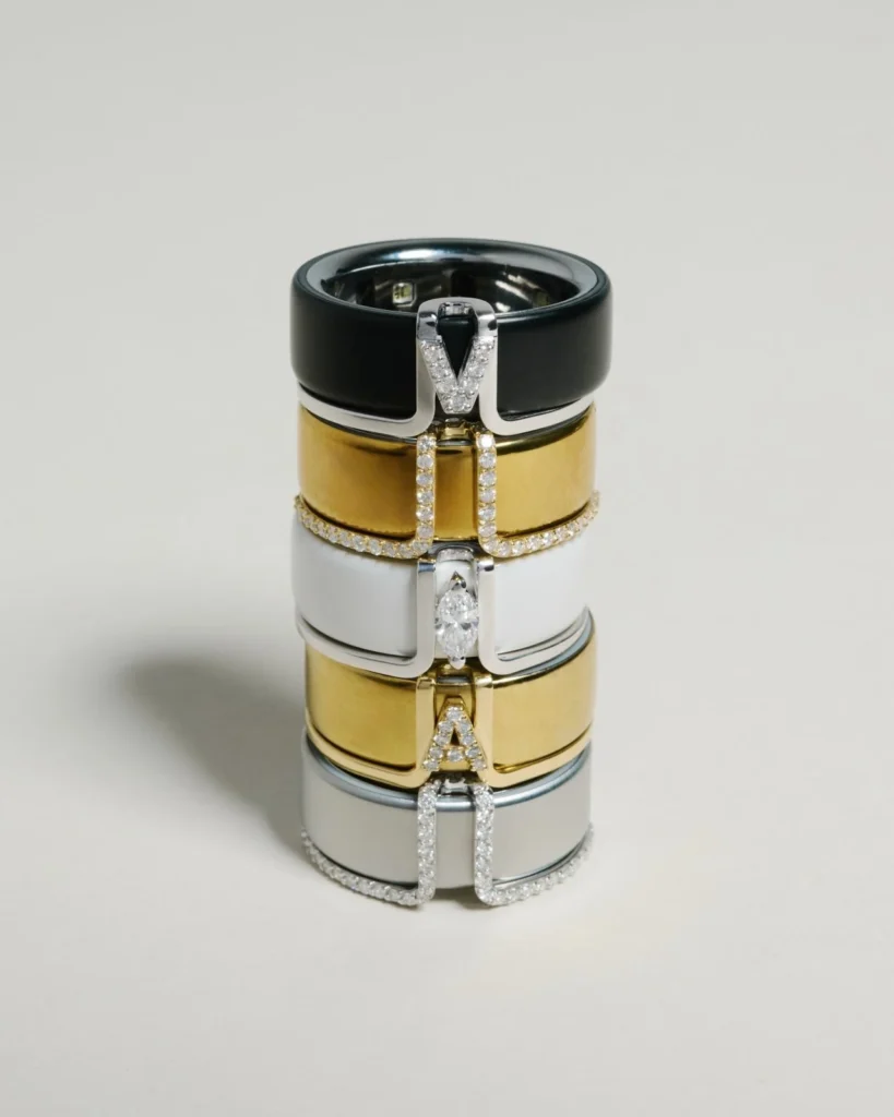 Stacked smart ring covers by LIL Milan featuring diamond-set initial letters, designed to fit Oura, Galaxy Ring and Ultrahuman Air smart rings.
