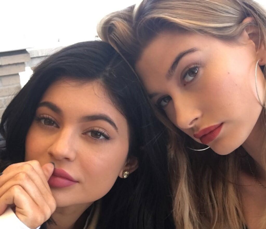 Close-up selfie of Kylie Jenner and Hailey Bieber with soft makeup and filtered lighting, characteristic of 2016 Instagram aesthetics. The image represents social media nostalgia, mid-2010s beauty trends and the resurgence of throwback content on TikTok and Instagram.