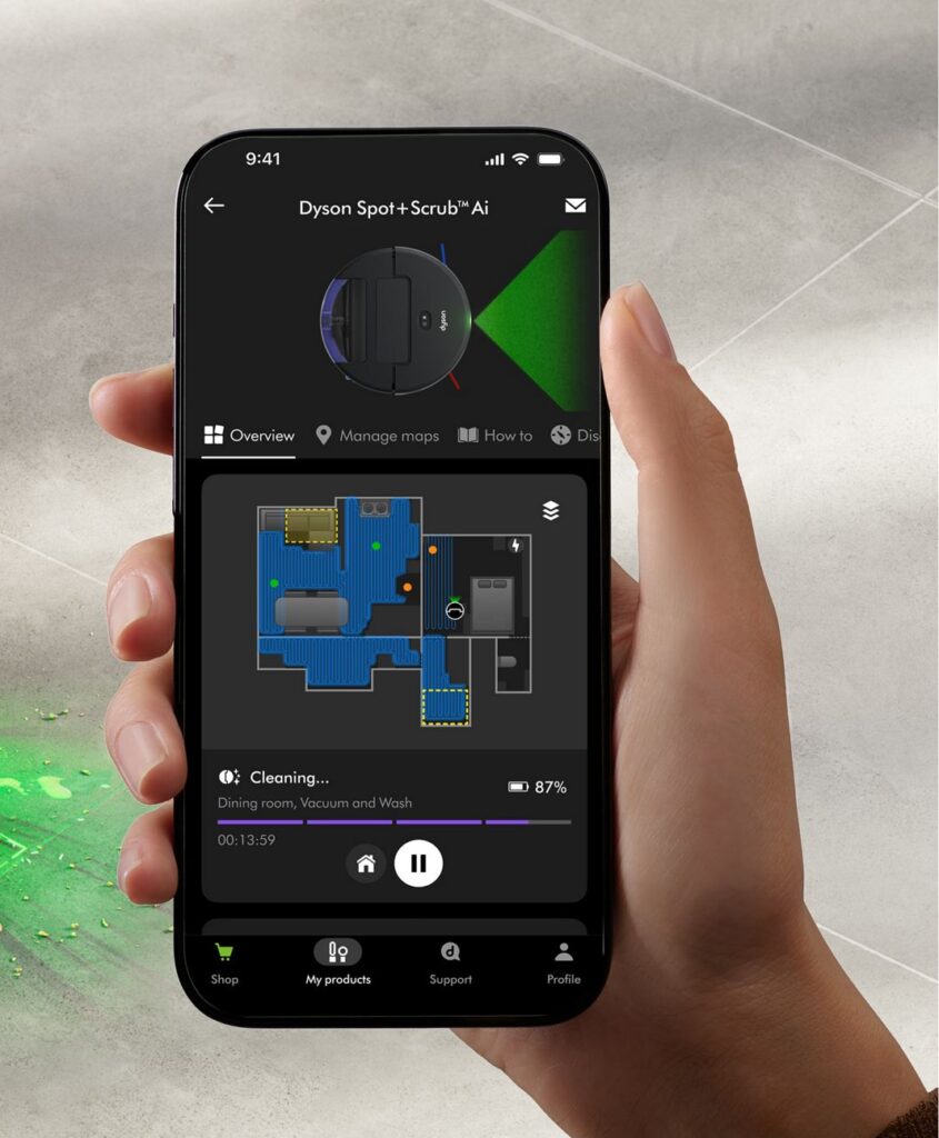 Smartphone displaying the MyDyson™ app with a live cleaning map of the Dyson Spot+Scrub™ AI robot vacuum, showing room coverage, stain detection and cleaning progress.