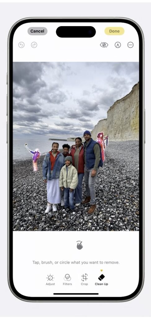 iPhone displaying Apple Intelligence Clean Up tool in the Photos app, removing unwanted background objects from a beach photo while preserving the main subjects.