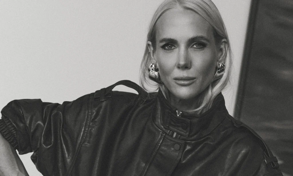 Black-and-white close-up portrait of SheerLuxe founder Georgie Coleridge Cole wearing a leather jacket and statement earrings, photographed in a minimalist setting, highlighting confidence and authority in modern fashion publishing.