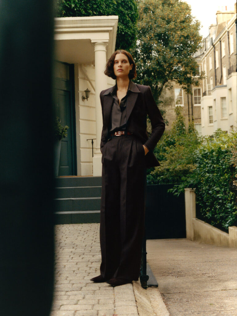 Full-length image of model in Knatchbull brown pinstripe tailored suit with wide-leg trousers, styled for modern womenswear tailoring.
