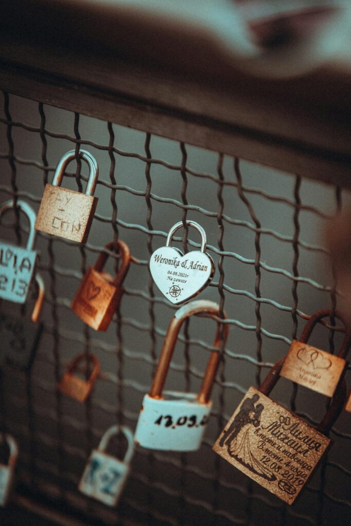 Close-up of engraved love padlocks attached to a metal fence, symbolising commitment, romantic traditions, Valentine’s Day love stories and travel romance.