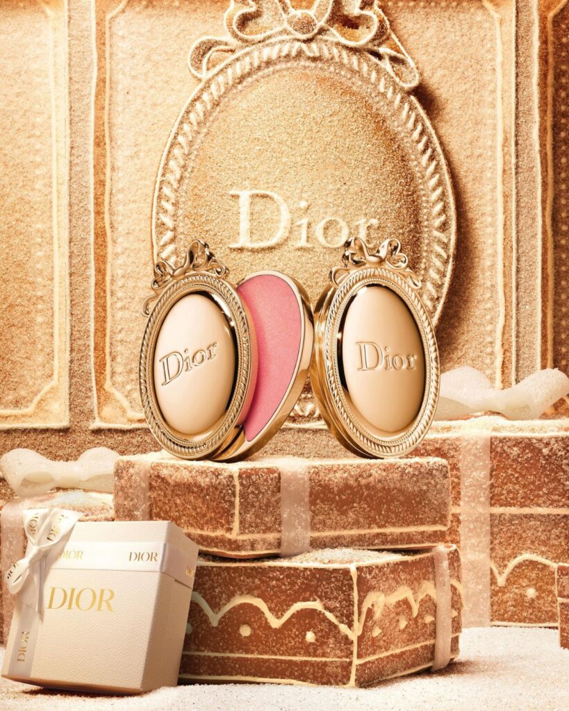 Two Dior Médaillon lip balms displayed on gingerbread gift boxes in the Dior Cinnamon Glaze Christmas 2026 campaign