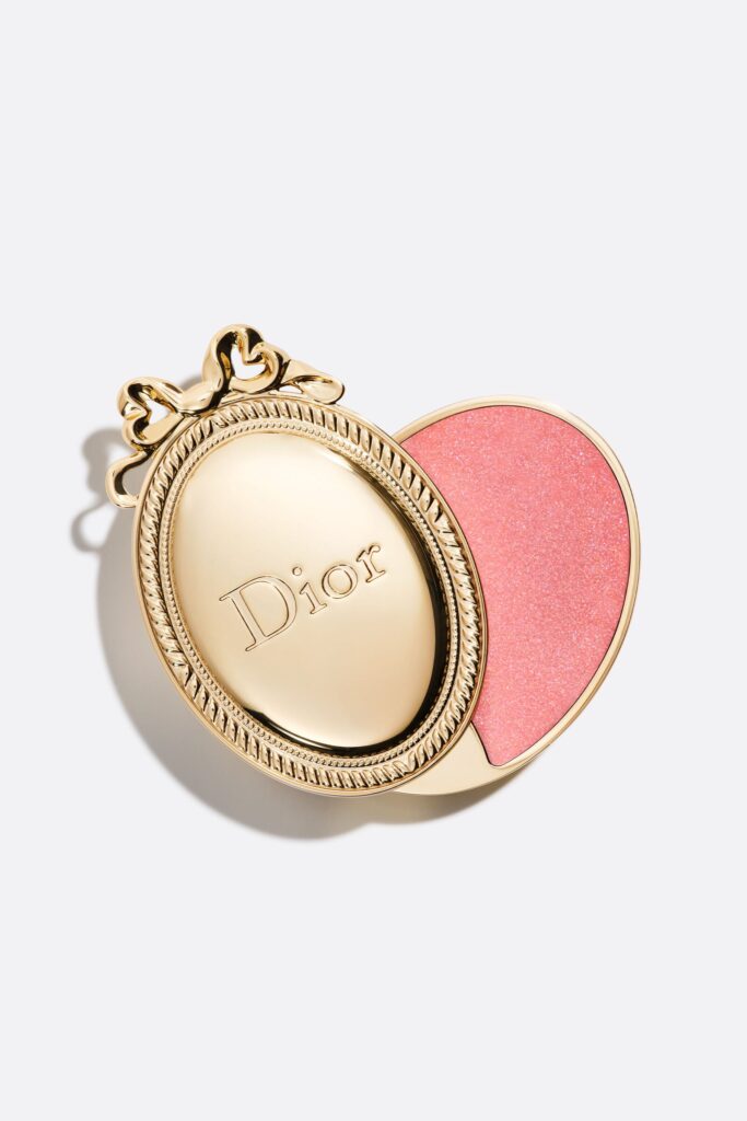 Dior Médaillon limited edition lip balm, a gold oval locket-style case with a bow, slid open to reveal a sparkling pink balm