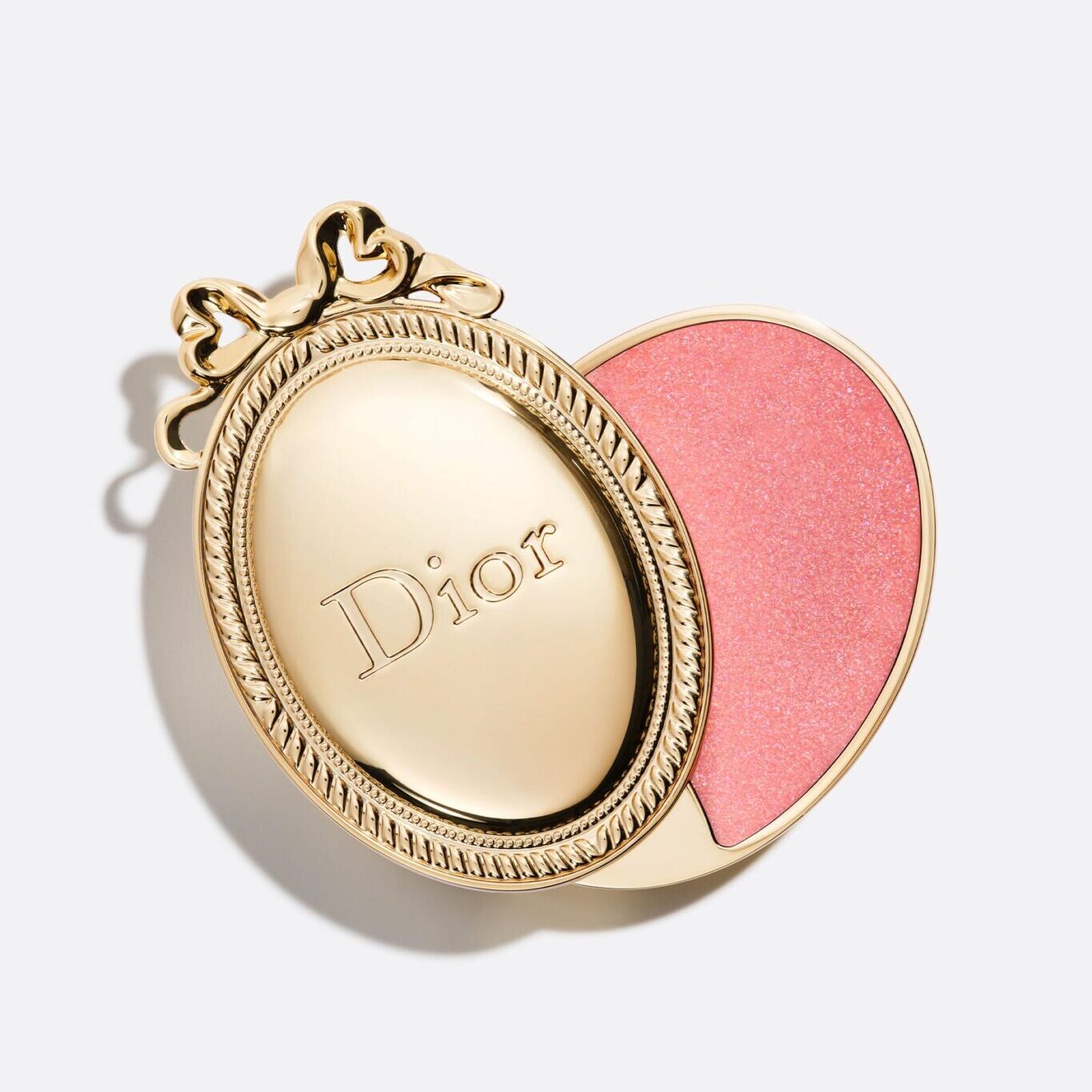 Dior Médaillon limited edition lip balm, a gold oval locket-style case with a bow, slid open to reveal a sparkling pink balm